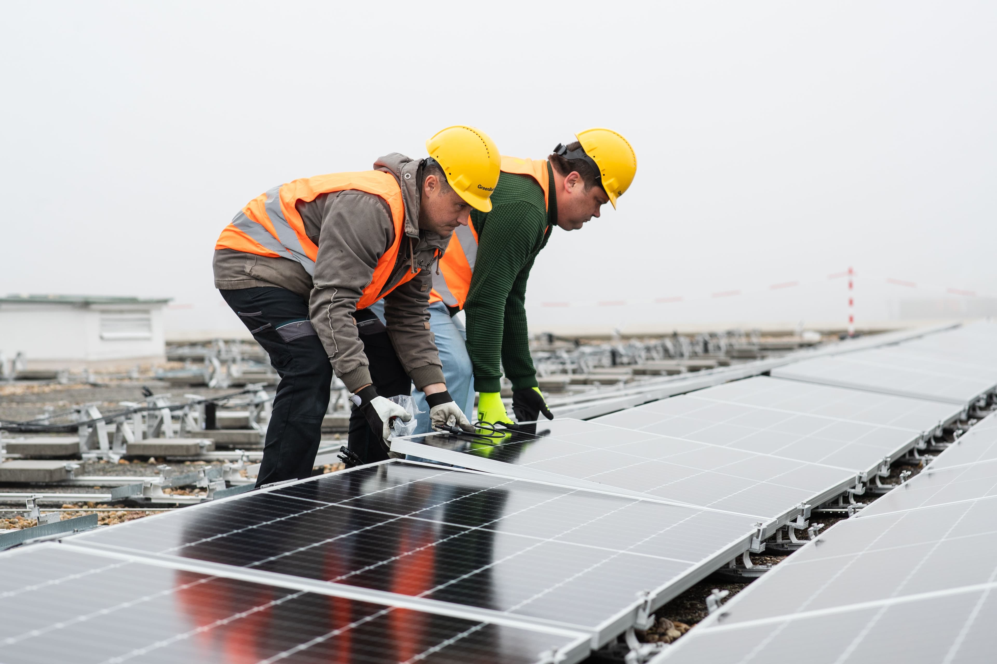 Greenbuddies workers installing a photovoltaic panel at the rooftop power plant construction site